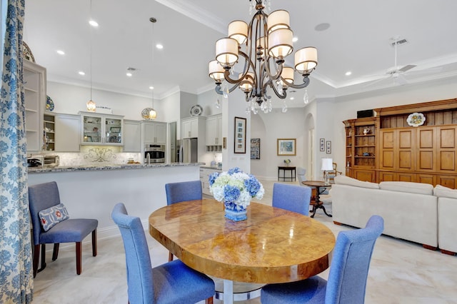 dining area featuring ceiling fan with notable chandelier and ornamental molding