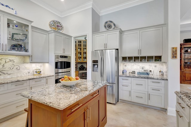 kitchen with light stone countertops, white cabinetry, tasteful backsplash, crown molding, and appliances with stainless steel finishes