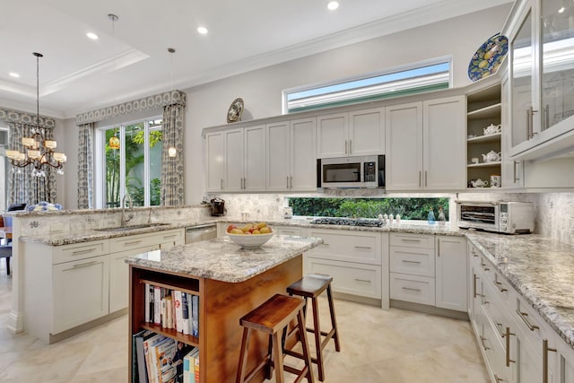 kitchen with sink, decorative light fixtures, a kitchen island, stainless steel appliances, and a chandelier