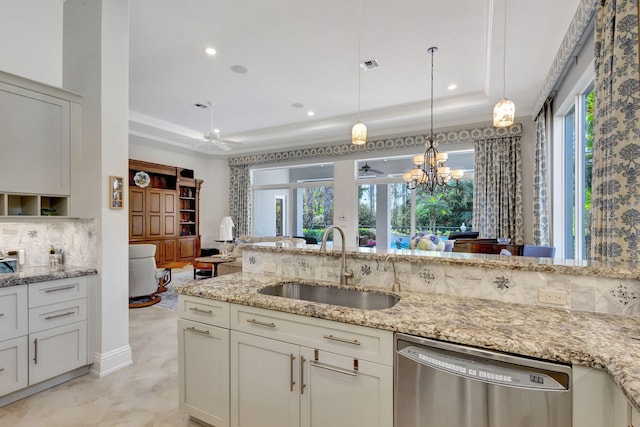 kitchen with a raised ceiling, sink, stainless steel dishwasher, decorative backsplash, and light stone counters