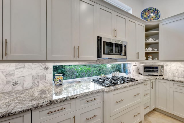 kitchen with decorative backsplash, light stone counters, and appliances with stainless steel finishes