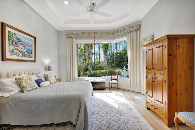 bedroom featuring ceiling fan, a raised ceiling, ornamental molding, and light hardwood / wood-style flooring