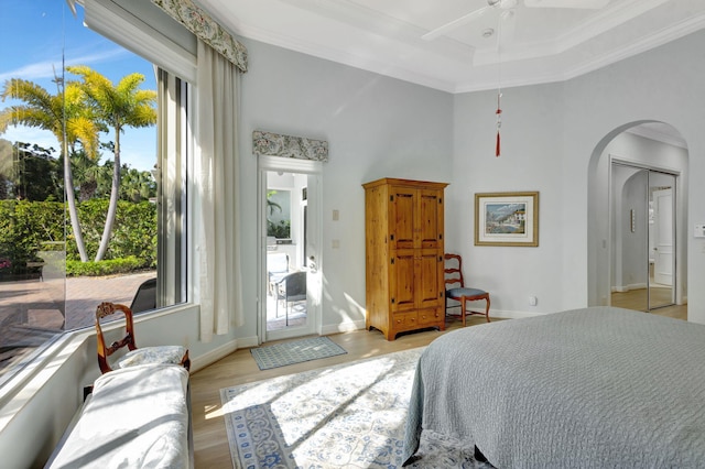 bedroom featuring multiple windows, light wood-type flooring, ceiling fan, and crown molding