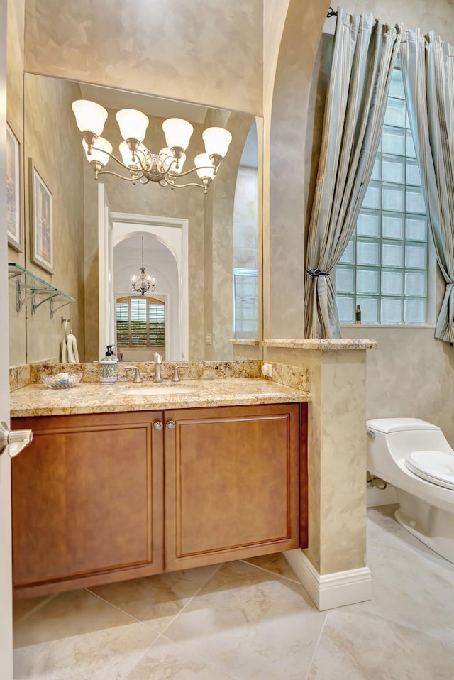 bathroom featuring vanity, toilet, and an inviting chandelier