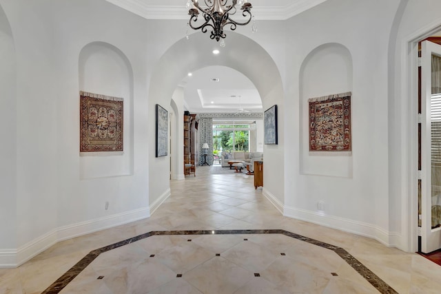 corridor with ornamental molding and a chandelier