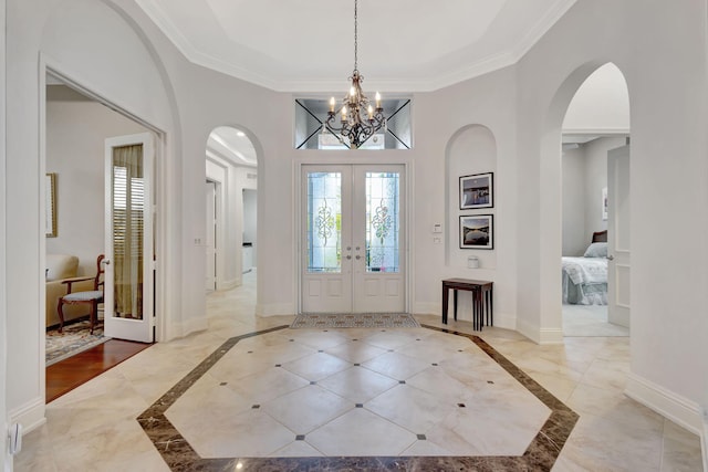 foyer with a chandelier, french doors, and ornamental molding