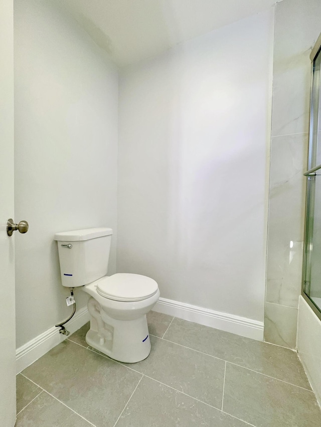 bathroom featuring tile patterned floors, toilet, and enclosed tub / shower combo