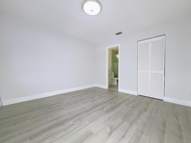 unfurnished bedroom with ensuite bath, light hardwood / wood-style floors, and a closet