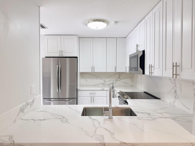 kitchen with white cabinets, appliances with stainless steel finishes, decorative backsplash, and sink