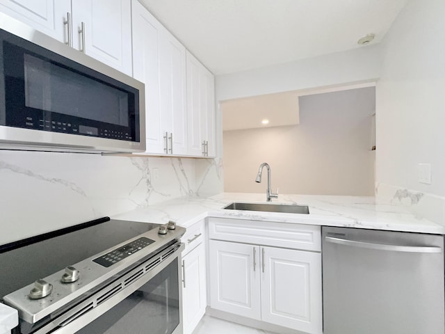 kitchen with white cabinets, appliances with stainless steel finishes, tasteful backsplash, and sink