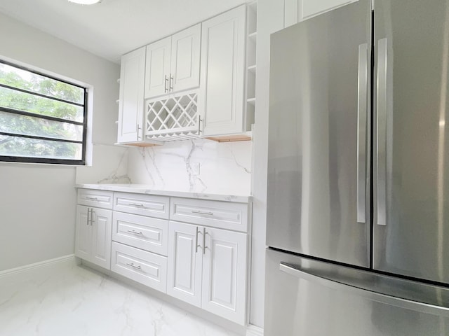 kitchen with white cabinets, stainless steel fridge, light stone countertops, and tasteful backsplash