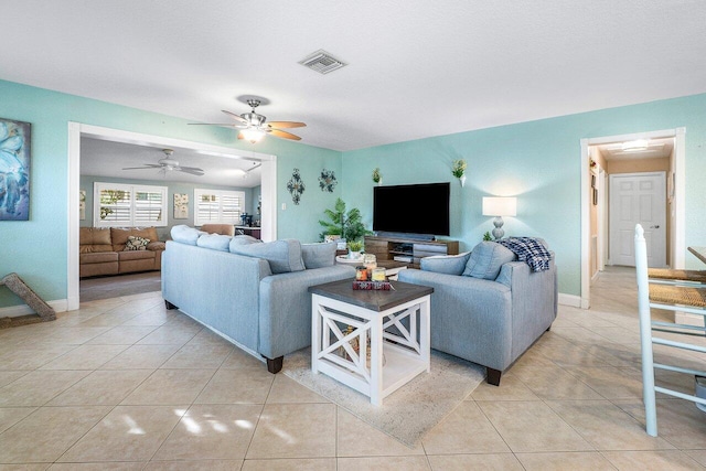 tiled living room with ceiling fan and a textured ceiling