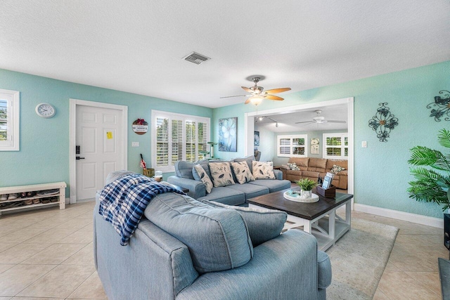 living room featuring a textured ceiling, ceiling fan, and light tile patterned flooring