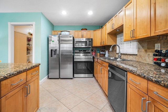 kitchen with stainless steel appliances, tasteful backsplash, dark stone countertops, and sink