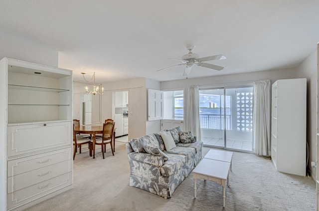 living room featuring light carpet and ceiling fan with notable chandelier