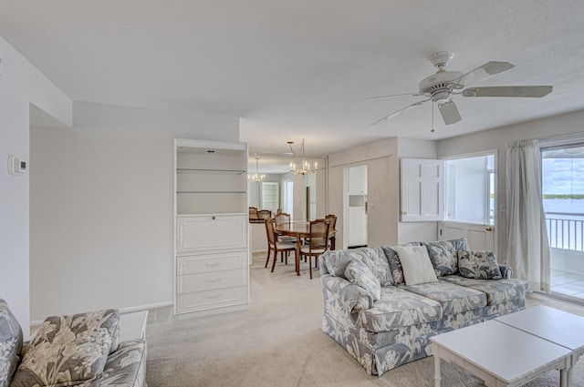 carpeted living room featuring ceiling fan with notable chandelier