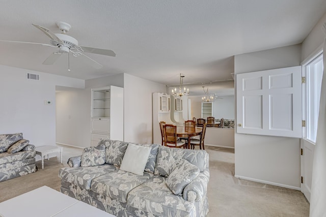 carpeted living room with ceiling fan with notable chandelier