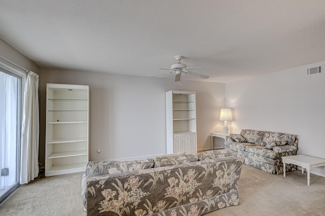 living room with a textured ceiling, light colored carpet, and ceiling fan