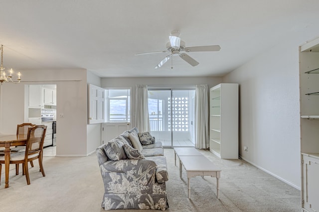 carpeted living room with ceiling fan with notable chandelier