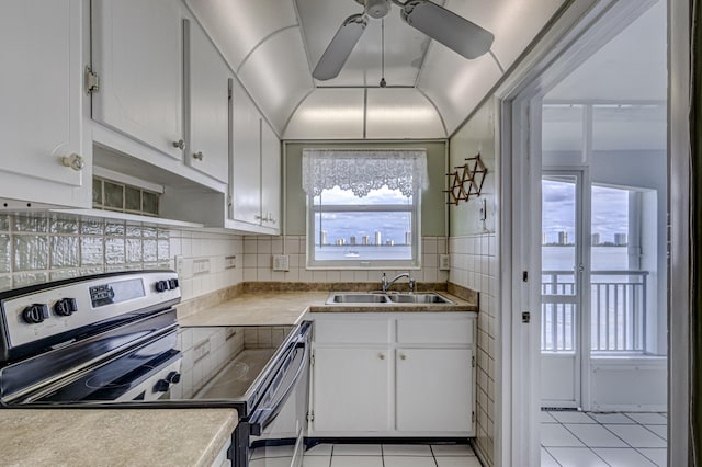 kitchen featuring stainless steel electric stove, white cabinetry, sink, and light tile patterned floors