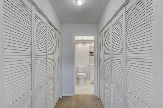 corridor with a textured ceiling and light carpet