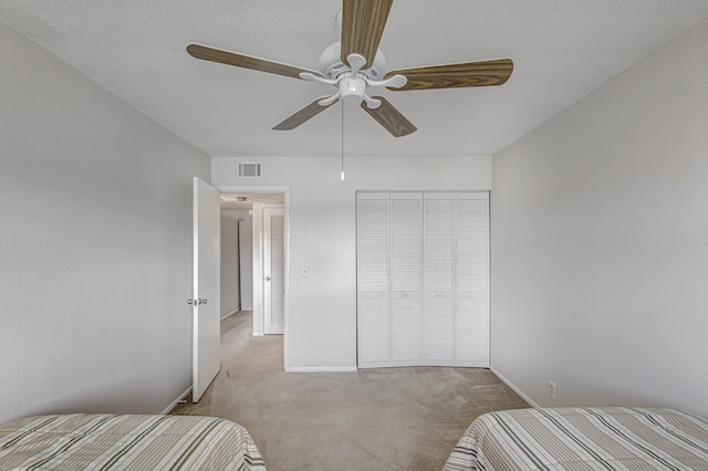 unfurnished bedroom featuring ceiling fan, light colored carpet, and a closet