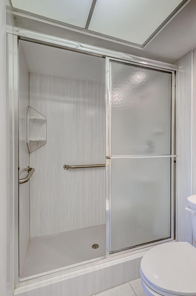 bathroom with toilet, tile patterned flooring, and walk in shower