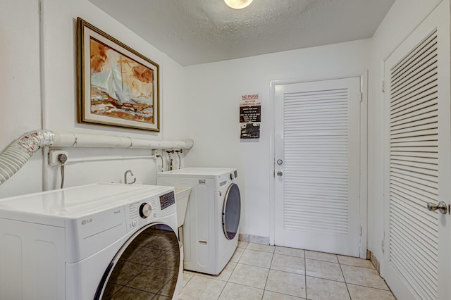 washroom with light tile patterned floors, a textured ceiling, and washer and clothes dryer