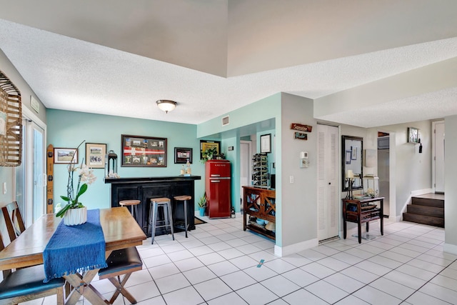 dining area featuring light tile patterned floors, a textured ceiling, and indoor bar