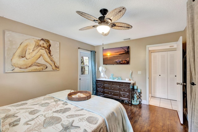 bedroom with a textured ceiling, a closet, dark hardwood / wood-style floors, and ceiling fan