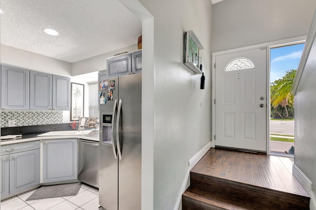 kitchen with sink, stainless steel appliances, tasteful backsplash, gray cabinets, and light tile patterned floors