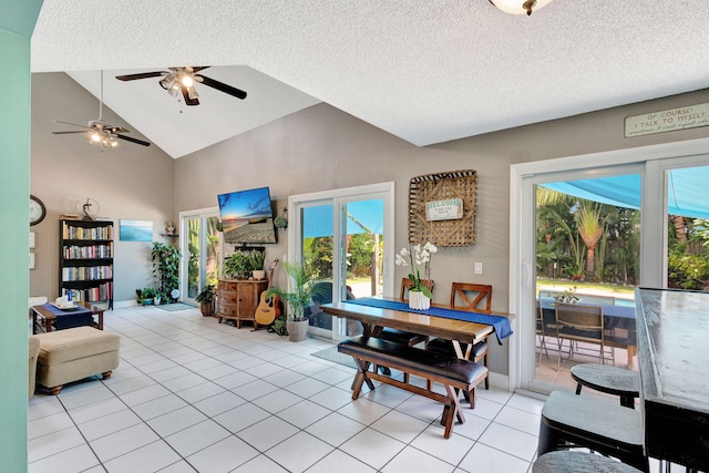 tiled living room with ceiling fan, a textured ceiling, and high vaulted ceiling