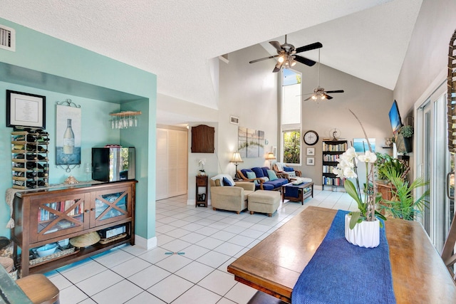 living room with ceiling fan, light tile patterned floors, a textured ceiling, and high vaulted ceiling