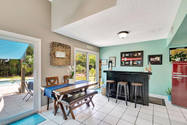 tiled dining space featuring a textured ceiling and bar area