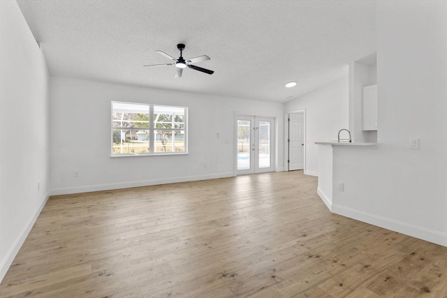 unfurnished living room featuring ceiling fan, light hardwood / wood-style floors, lofted ceiling, and a textured ceiling