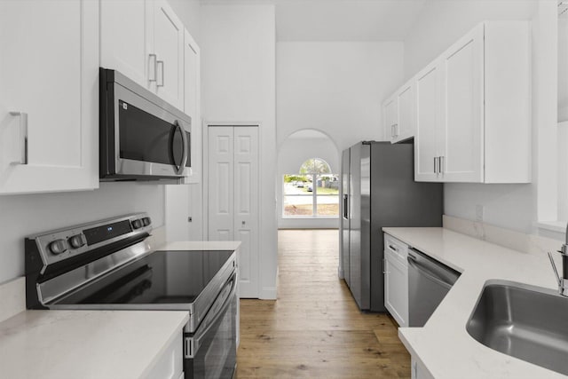 kitchen featuring white cabinets, sink, light wood-type flooring, and stainless steel appliances