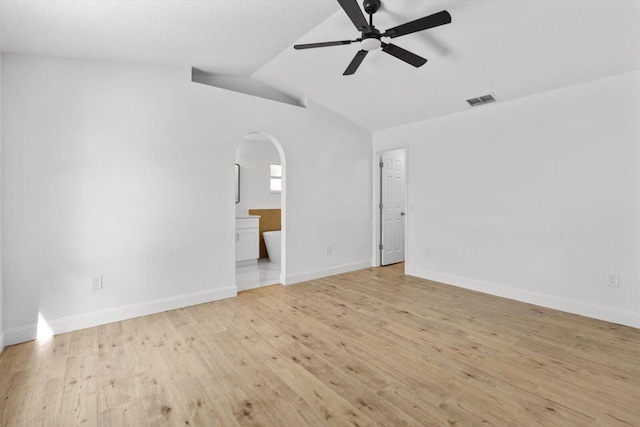 empty room with ceiling fan, vaulted ceiling, and light hardwood / wood-style flooring