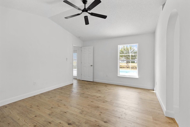 unfurnished room featuring a textured ceiling, light wood-type flooring, vaulted ceiling, and ceiling fan