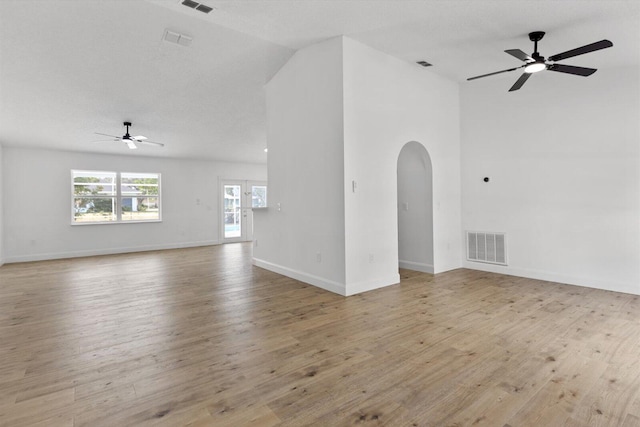 empty room featuring ceiling fan, light hardwood / wood-style floors, lofted ceiling, and a textured ceiling