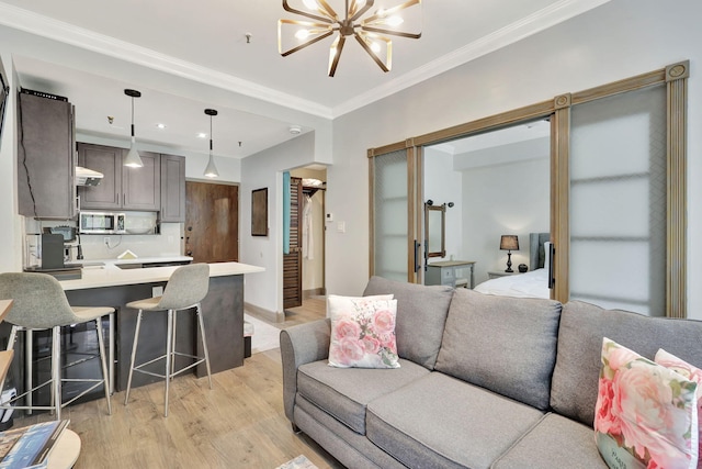 living room with a chandelier, light wood-type flooring, and crown molding