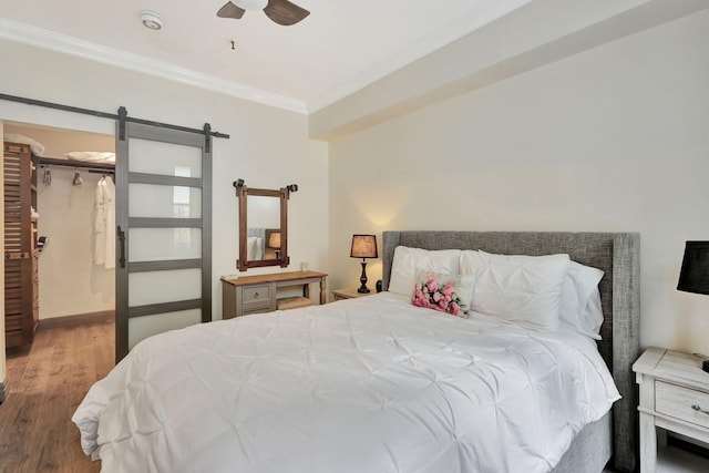 bedroom featuring ceiling fan, a spacious closet, crown molding, hardwood / wood-style floors, and a closet