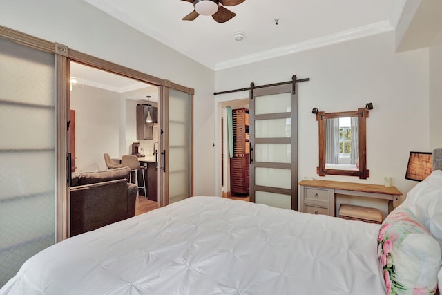 bedroom featuring ceiling fan, a barn door, ornamental molding, and a closet