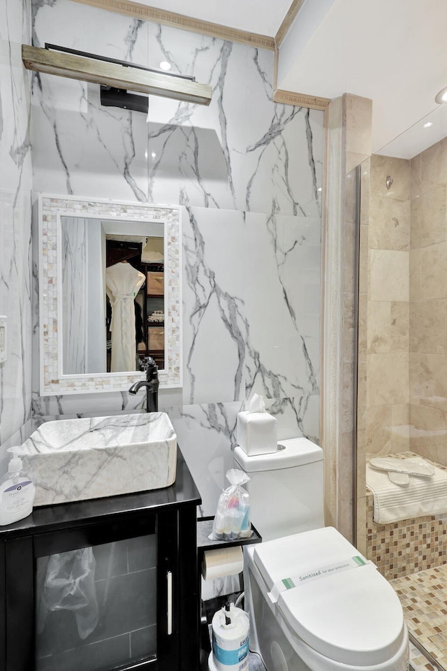 bathroom featuring vanity, toilet, a shower with door, and tile walls