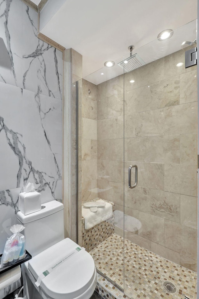 bathroom with a shower with shower door, tile walls, and toilet