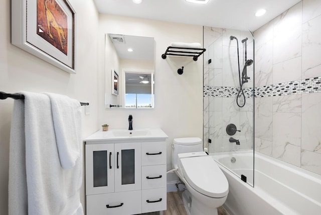 full bathroom with hardwood / wood-style floors, vanity, toilet, and tiled shower / bath