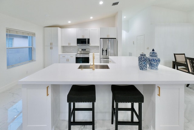 kitchen featuring a kitchen bar, a large island with sink, and stainless steel appliances