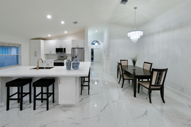 kitchen with sink, stainless steel appliances, a kitchen breakfast bar, pendant lighting, and white cabinets