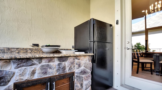 kitchen featuring stone counters and black refrigerator