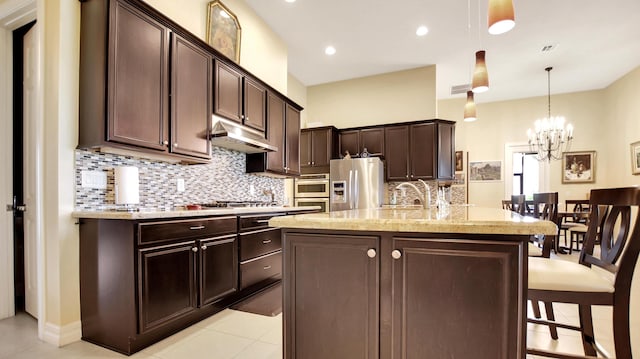 kitchen featuring dark brown cabinetry, an inviting chandelier, an island with sink, decorative light fixtures, and appliances with stainless steel finishes