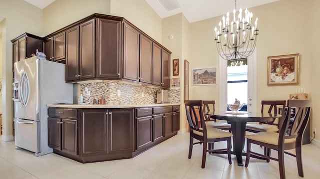 kitchen with dark brown cabinets, backsplash, and stainless steel refrigerator with ice dispenser